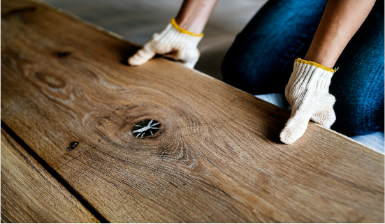 Trabajador instalando láminas de madera para reforma de piso